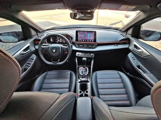 Interior completo do carro com bancos de couro, painel e volante à esquerda